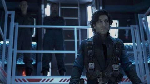Keon Alexander (Marco Inaros) stands at a railing in a blue room in The Expanse