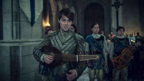 a young dark-haired man holding a lute walks into a banquet hall in The Witcher