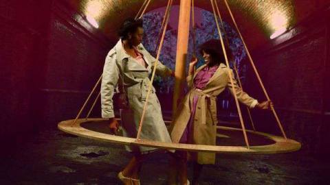 Two women stand inside a large spinning top