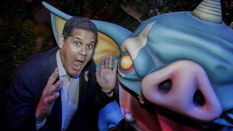 Reggie Fils-Aime makes a funny face next to an oversized statue of a bokoblin, a cartoony creature from the Legend of Zelda