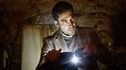 A severe-looking man in a suit manipulates a bright light in 30 Coins