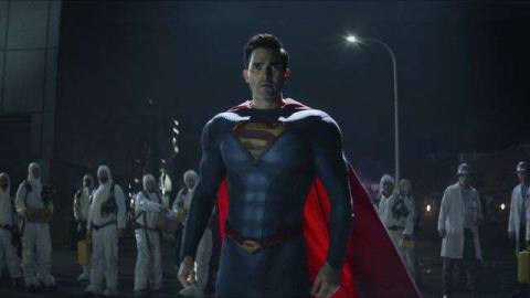 Tyler Hoechlin in his Superman costume stands in front of a group of hazmat-suited workers at night in Superman &amp; Lois