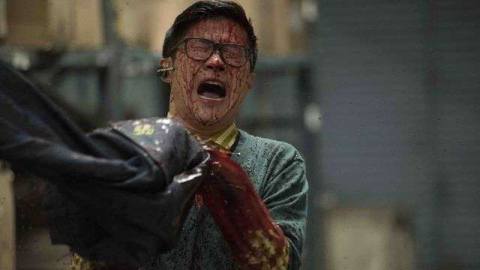 A bloodied man in glasses screams as he holds onto a pair of jeans that might be eating his arm maybe?