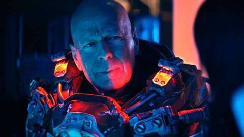 Bald Bruce Willis, generically scowling in blue and red light in Cosmic Sin