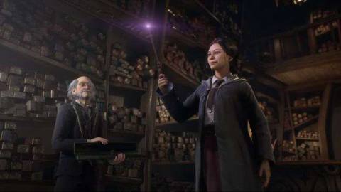 a Hogwarts student holds a wand in a wand shop as an elderly man looks on in Hogwarts Legacy