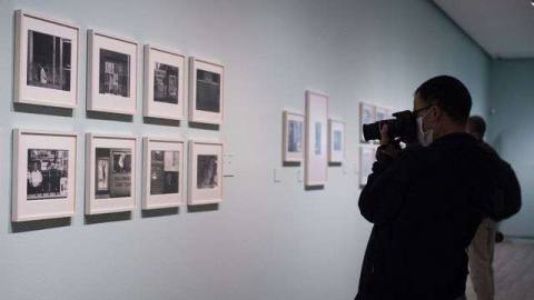 a person takes a photo of eight photographs on the wall at an art gallery