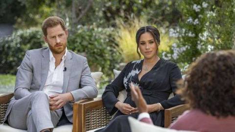 Prince Harry and Meghan Markle sit in chairs opposite Oprah