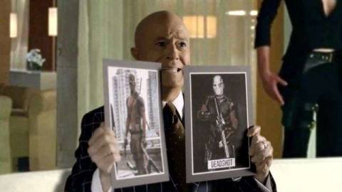 Stephen Colbert holds up pictures of Deadpool and Deadshot