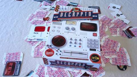 The box for the board game Decrypto sits at top a pile of the games cards and components.