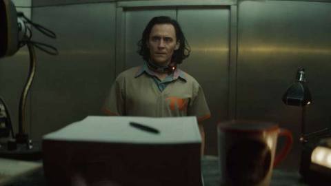 Loki faces a computer screen in a TVA prison jumpsuit from Loki on Disney Plus