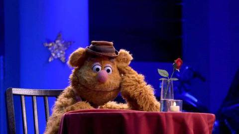 Fozzy Bear sits dejected at a restaurant table in the Muppets Now! premiere. 