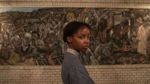 Cora (Thuso Mbedu) stands in front of an elaborate mural in an underground railroad station in Barry Jenkins’ The Underground Railroad