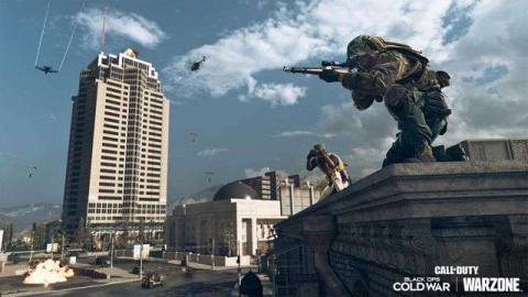 A Call of Duty: Warzone player sits on a rooftop in front of Nakatomi Plaza