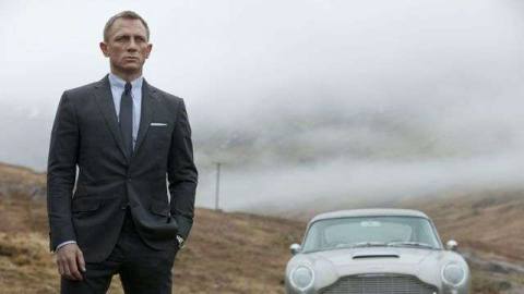 Daniel Craig as James Bond standing in front of a car in Skyfall