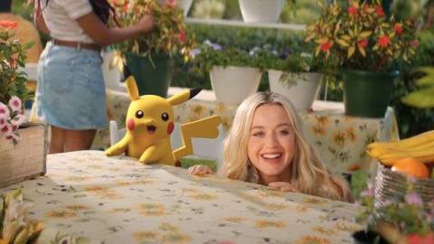 Katy Perry and Pikachu crouch behind table in the music video for “Electric.”