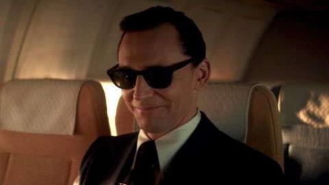 Tom Hiddleston as Loki as D.B. Cooper wearing sunglasses and smiling on a plane