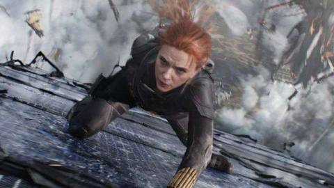 Black Widow slides her way down the side of a building amid falling debris in the Marvel Studios film Black Widow.