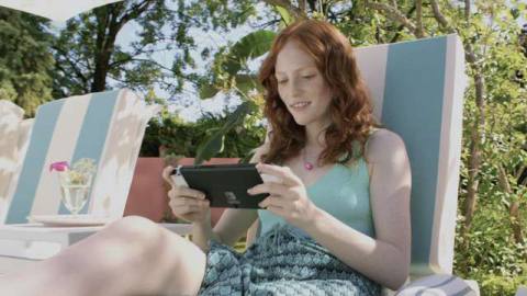 a young person sitting on a pool chair while playing their Nintendo Switch 