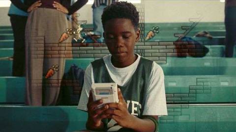 Young LeBron James plays a Game Boy in a still from Space Jam: A New Legacy