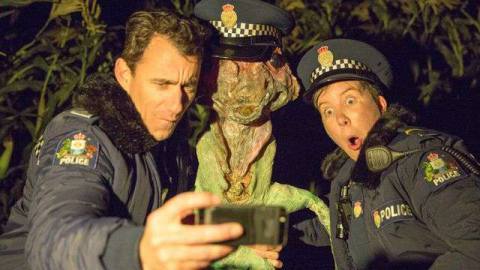 Wellington Paranormal cops Minoque and O’Leary take a nighttime selfie with an alien named “Extraterrestrial Flora”