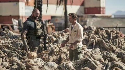 Dave Bautista and Zack Snyder stand in a field of corpses on the Army of the Dead set