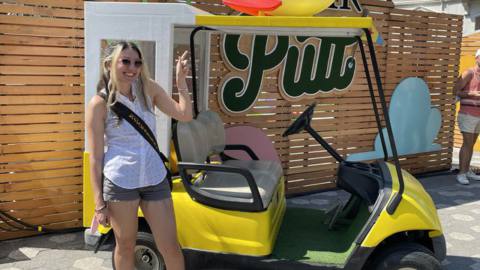 petrana stands in front of a golf cart stylized to look like the pizza planet delivery car