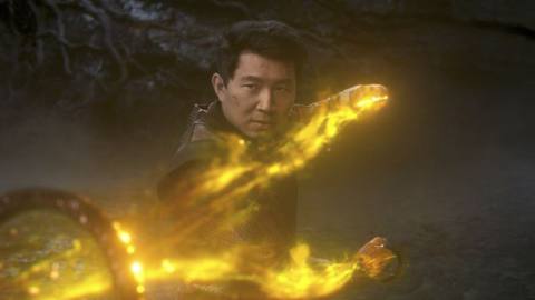 Simu Liu wields the Ten Rings, surrounded by yellow fire, as Shang-Chi in Shang-Chi and the Legend of the Ten Rings. 