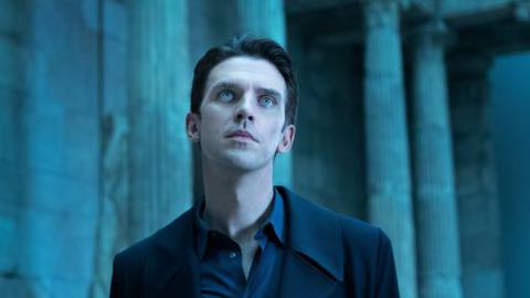 Dan Stevens, as the AI Tom in I’m Your Man, stands in a blue-lit columned ampitheater, looking upward