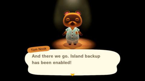 Tom Nook in a dark room, only illuminated by a spotlight, notes that the Animal Crossing: New Horizons island backup has been enabled