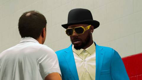 a guy in a white shirt with a bald spot on the back of his head talks to a large NBA player in flashy street clothes and garish sunglasses