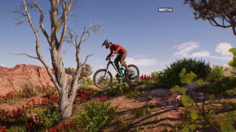 A woman on a mountain bike leaps over some desert brush in Riders Republic