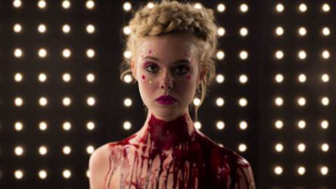 A woman looks at the camera, while blood drips down her body in Neon Demon