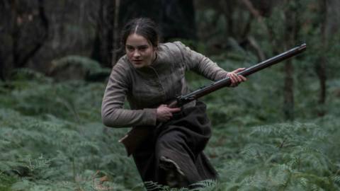 Clare (Aisling Franciosi) racing through a forest and touting a rifle in The Nightingale.&nbsp;