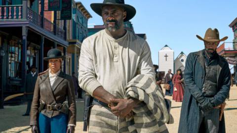 Regina King, Idris Elba, and LaKeith Stanfield in Western duds, arrayed across the street of an Old West town in The Harder They Fall.