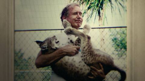 Carole Baskin’s former husband Don Lewis in a file photo, making a face as he cradles a lynx that’s pawing at his face