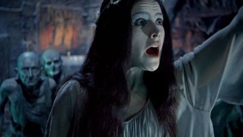 A woman in a flower crown screams while two monstrous humanoids crouch behind her in Viy