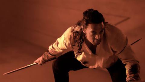 JASON MOMOA as Duncan Idaho in the movie DUNE standing in an attack position with two sticks