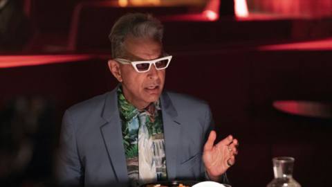 Jeff Goldblum wearing white frames in a grey suit in season 5 of Search Party.