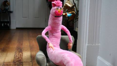 A pink LongFurby sitting in an armchair