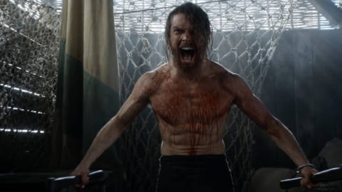a blonde, shirtless man wielding two hatches and dripping in blood