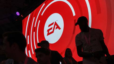 The silhouettes of attendees are seen standing in front of an Electronic Arts Inc. (EA) logo