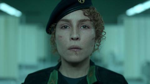 Noomi Rapace stares into the camera wearing military uniform