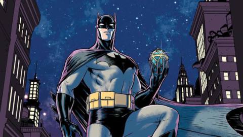 Batman holds a sparkling Fabergé egg, standing in front of a starry night sky and buildings with warmly glowing windows. His cape billows dramatically. From the cover of Batman: Universe #1 (2019).