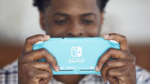 A Black man holding a turquoise Nintendo Switch Lite