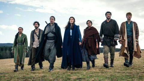 The core Wheel of Time cast — Nynaeve, Mat, Lan, Moiraine, Egwene, Perrin, and Rand — walking across a field