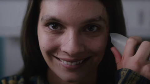 A character in the movie Smile with a wide grin and a shard of glass