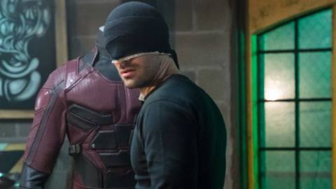 Daredevil (Charlie Cox) in his black ninja costume looking at the red daredevil costume from the 2015 Daredevil series.