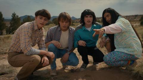 Noah Schnapp as Will Byers, Charlie Heaton as Jonathan Byers, Finn Wolfhard as Mike Wheeler, and Eduardo Franco as Argyle, looking into the distance