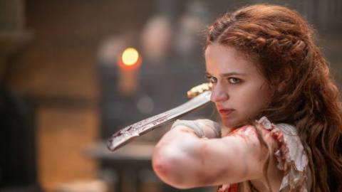 the princess, as played by joey king, wielding a bloody sword