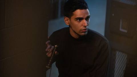 Rish Shah as Kamran in Ms. Marvel. He’s looking around the edge of a wall covertly.